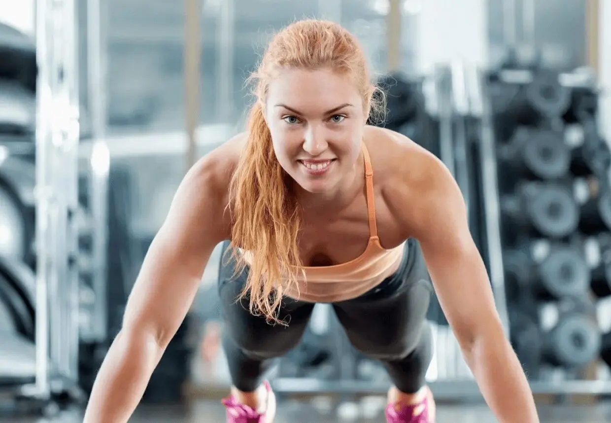12 Woman doing push-up in gym setting.